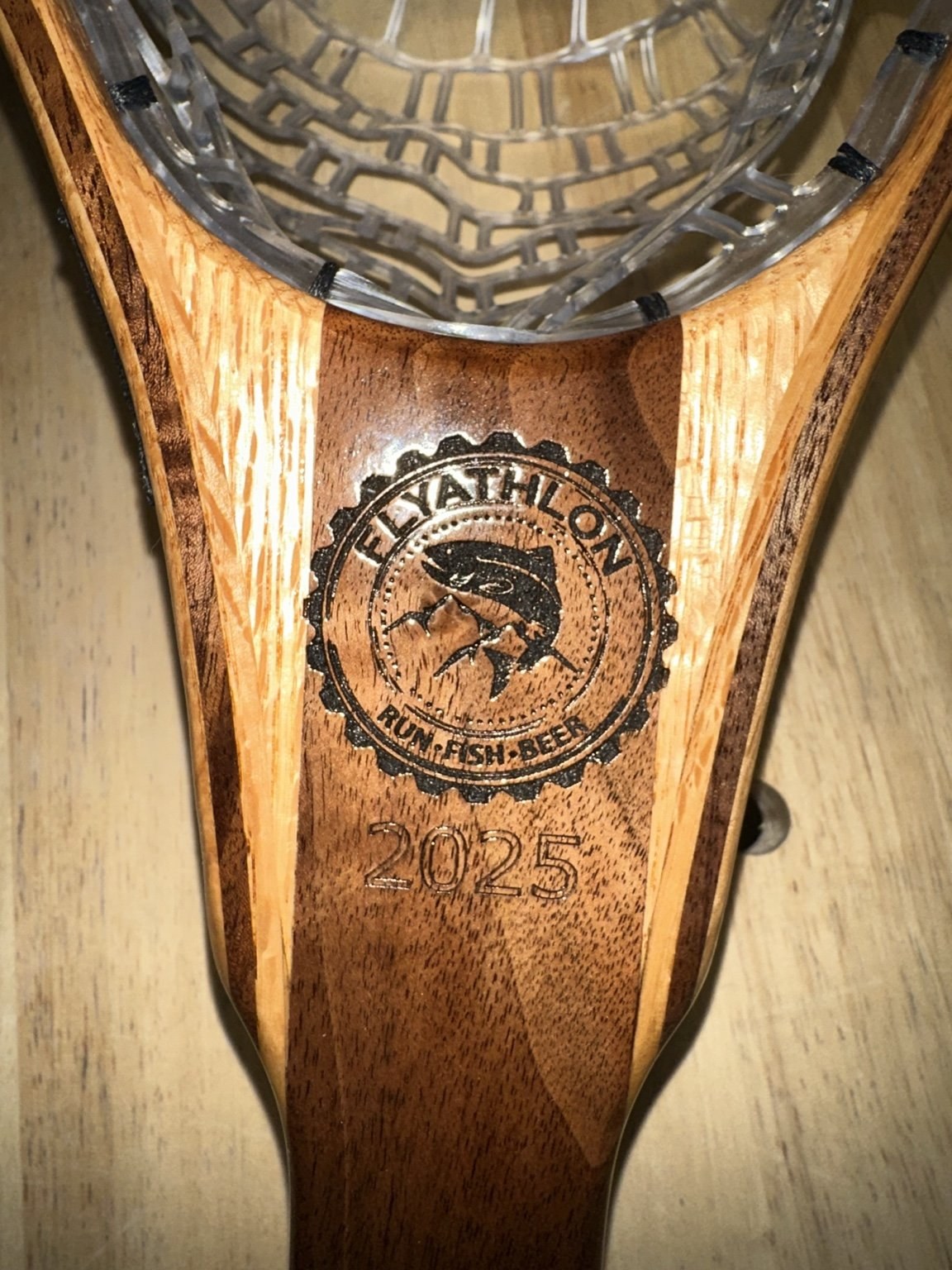 Close-up of a Flyathlon logo laser-engraved on a figured handle